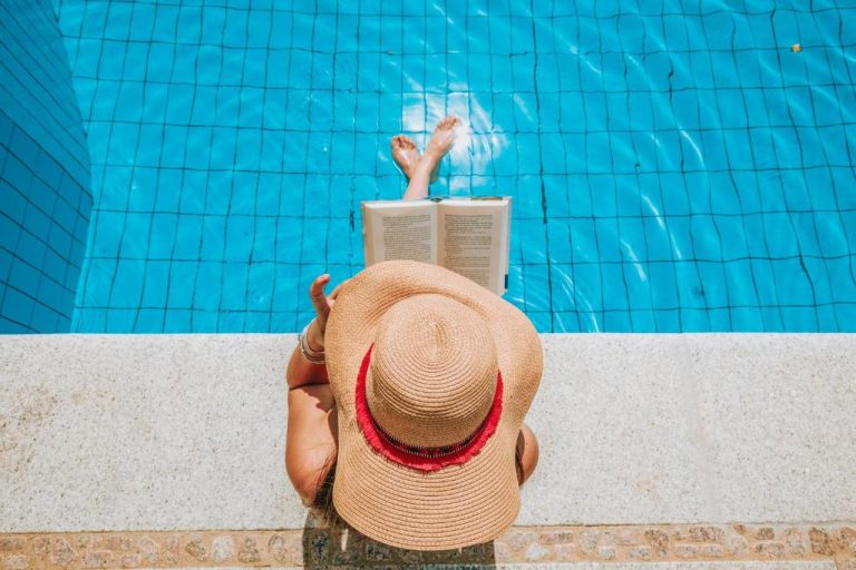 Mujer leyendo un libro sentada al borde de la piscina exterior del Hotel La Bitta Bovis Hotels