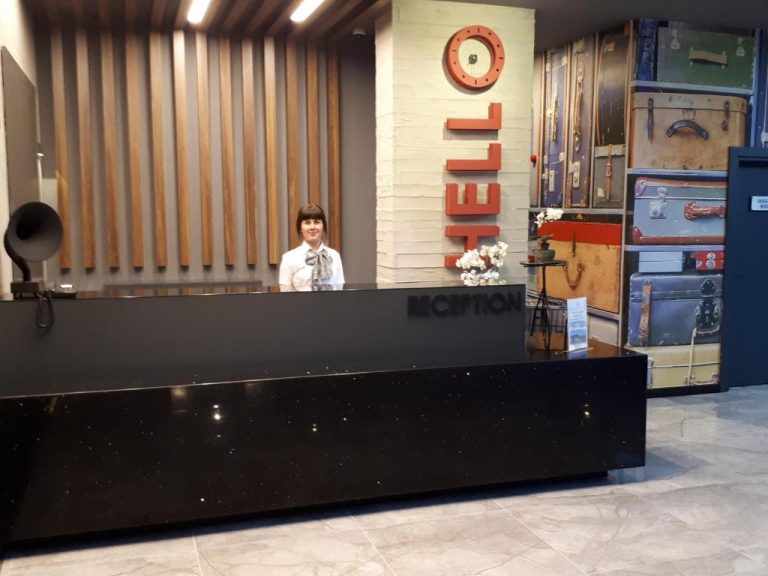 Recepción moderna del Ramira City Hotel Adult Only con decoración vintage de maletas y letrero Hello