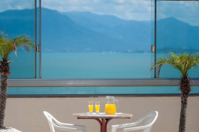 Terraza con mesa y zumo de naranja con vistas al mar y montañas en Rede Andrade Cecomtur