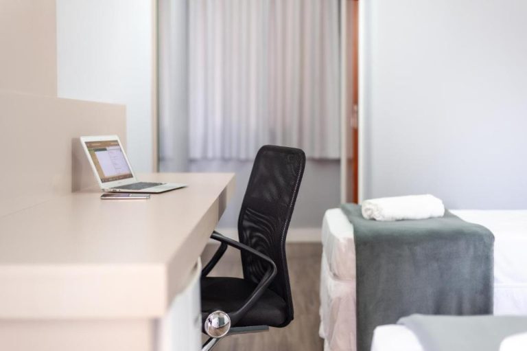 Escritorio de trabajo con laptop y silla ergonómica en habitación del Rede Andrade Cecomtur