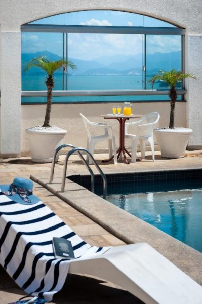 Piscina exterior con tumbonas y vista panorámica al mar en Rede Andrade Cecomtur