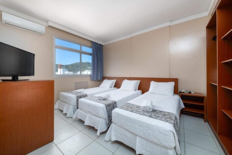 Habitación triple con tres camas individuales y televisor en Hotel Rede Andrade Cecomtur