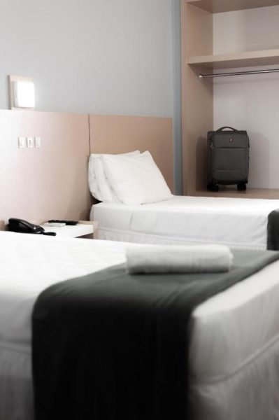 Habitación twin con dos camas individuales y maleta en el armario del Rede Andrade Cecomtur