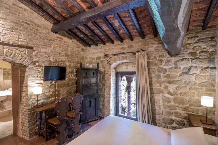 Habitación rústica con paredes de piedra y vigas de madera en TH Perugia Castello di Monterone