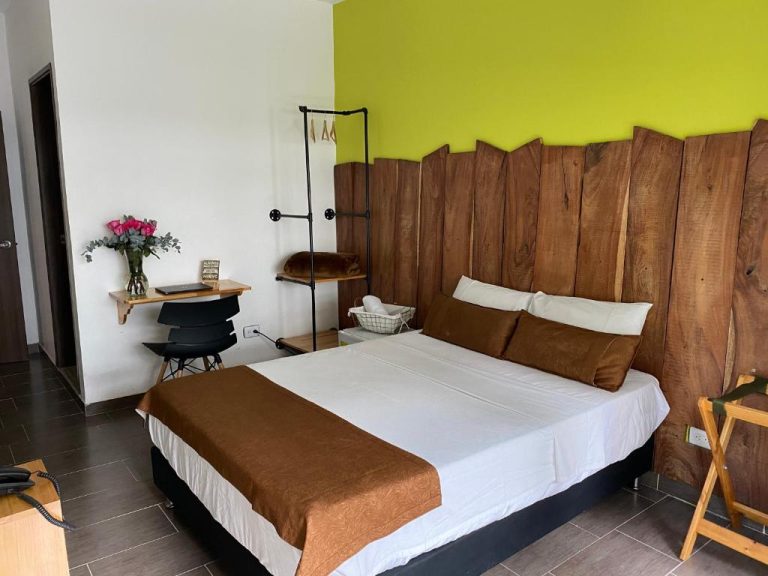 Habitación doble con cabecero de madera rústica y pared verde en Rivière Boutique Hotel