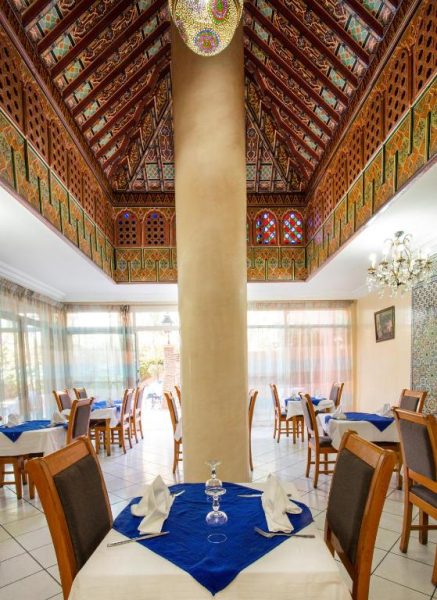 Elegante restaurante del Hotel Akabar con techo decorado en estilo árabe y mesas con mantel azul