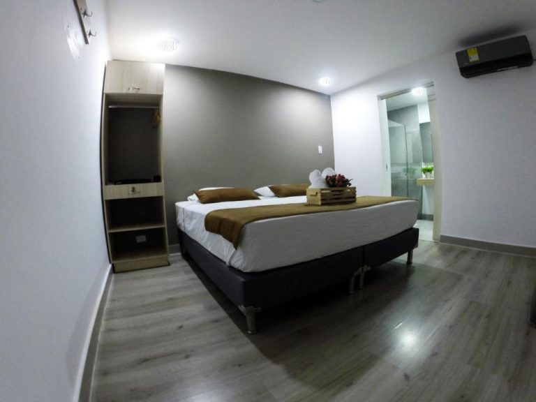 Habitación doble con cama matrimonial y baño en suite del Hotel Boutique Plaza con suelo de madera