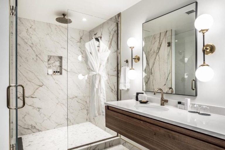 Baño de lujo con ducha de mármol blanco y tocador de madera en el Bottleworks Hotel