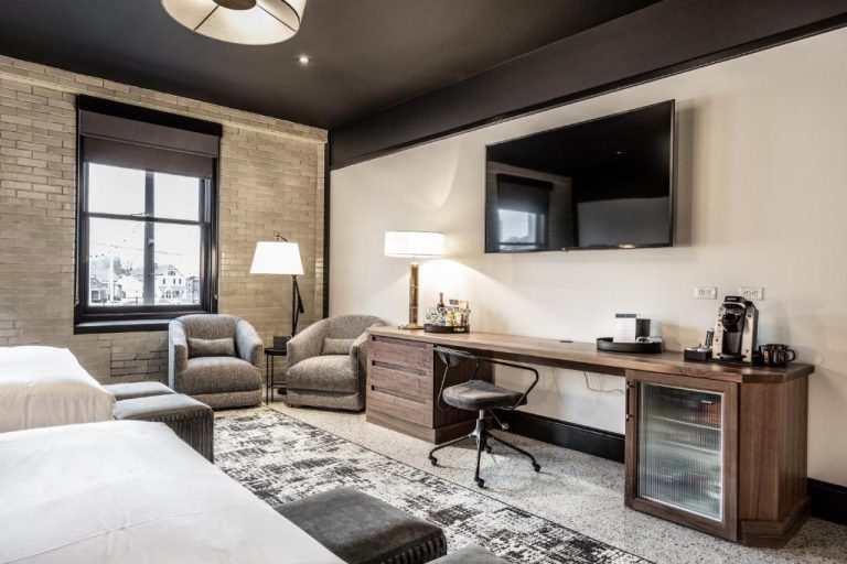 Habitación moderna con escritorio de madera, TV de pantalla plana y mini nevera en Bottleworks Hotel