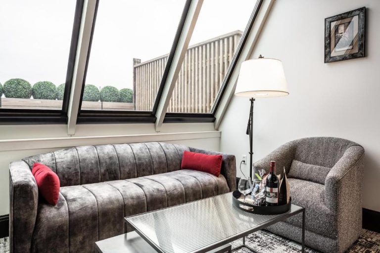 Sala de estar con sofá de terciopelo gris y ventanas inclinadas en Bottleworks Hotel