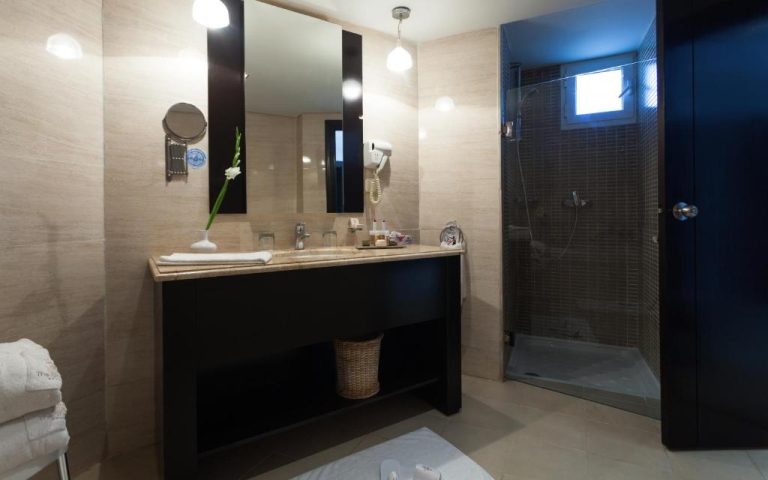 Baño moderno con ducha de cristal y encimera de mármol en el hotel The Sindbad