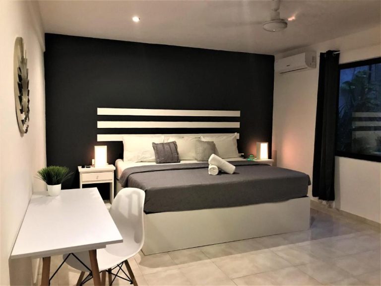 Habitación doble moderna con pared negra y cama king size en Che Suites Playa del Carmen