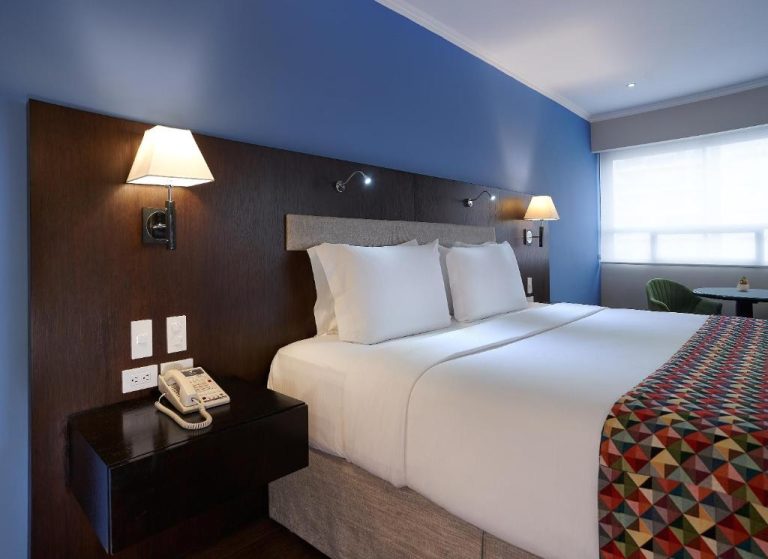Habitación con cama king size y pared azul en el Hotel Oro Verde Guayaquil