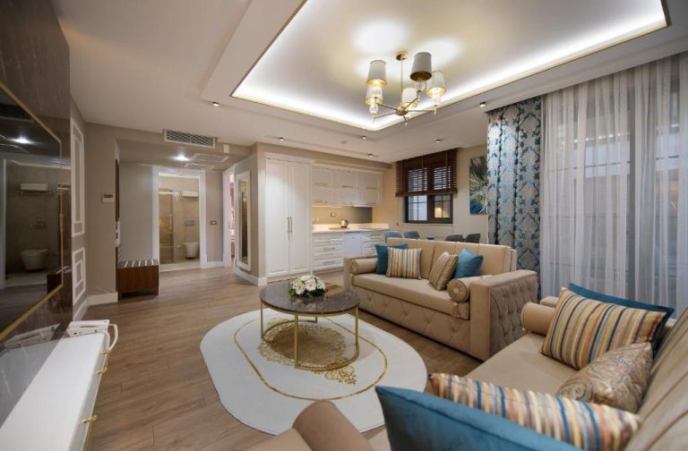 Amplio salón de suite de lujo con sofás beige y cojines turquesa en Elysium Green Suites