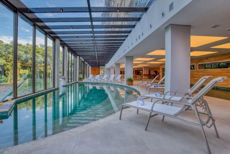 Piscina climatizada cubierta con techo de cristal y tumbonas del Wyndham Gramado Termas Resort & Spa