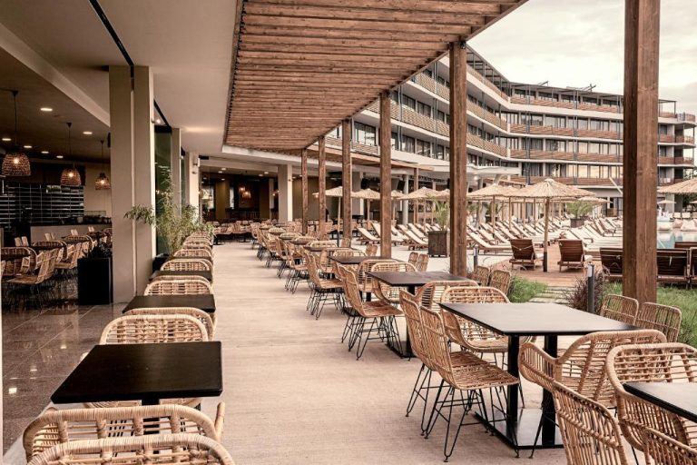 Terraza restaurante con sillas de ratán y mesas negras junto a la piscina del Sunny Beach Club Adults Only
