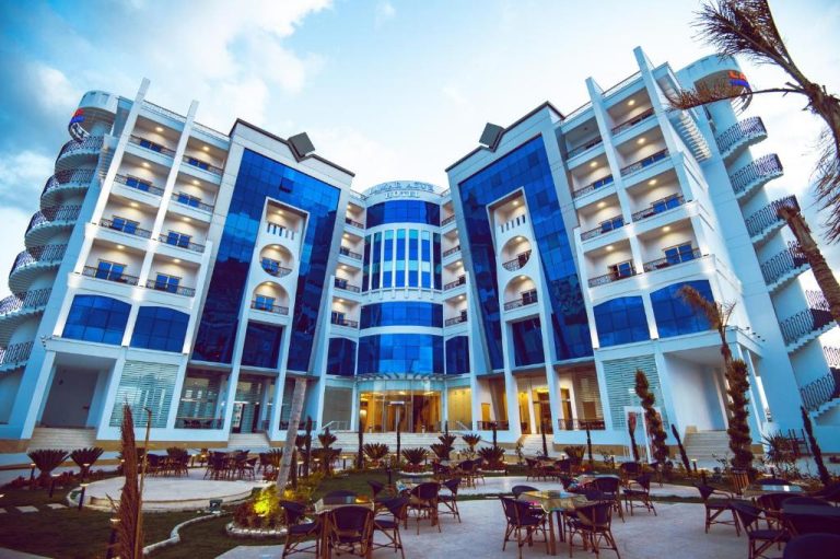 Fachada exterior del Lamar Azur Hotel con patio, terraza y cristales azules iluminados al atardecer