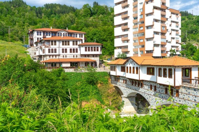 Fachada exterior del Spa Complex Aleksandar con puente de piedra y edificios tradicionales entre vegetación