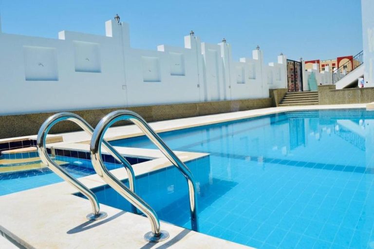 Piscina exterior con escalerillas de acero y agua cristalina en el Lamar Azur Hotel