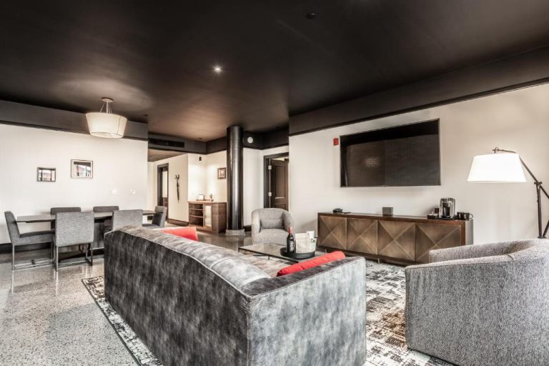 Amplia suite del Bottleworks Hotel con sofá, televisión de pared y zona de comedor en estilo moderno