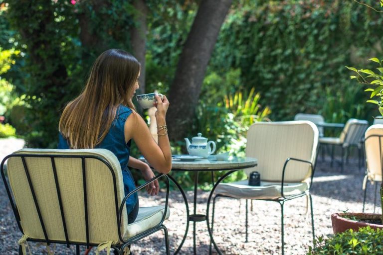 Mujer disfrutando de un té en la terraza jardín del Hotel Boutique Le Reve rodeada de vegetación