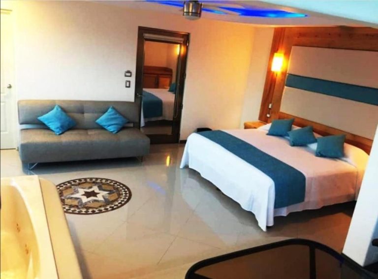 Suite con cama doble, sofá azul y jacuzzi integrado en el Hotel Blue Star Cancun