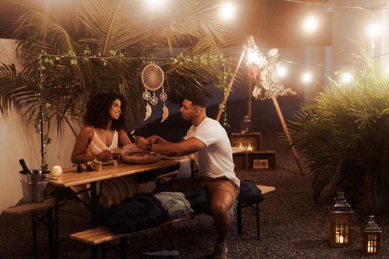 Cena romántica al aire libre con luces decorativas en The Palm Leaf Apartments, ambiente íntimo y acogedor
