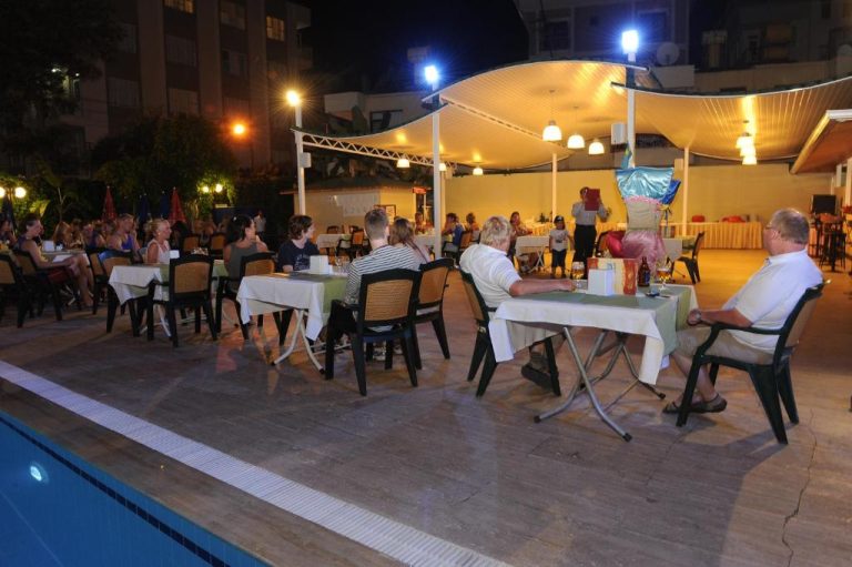Cena al aire libre junto a la piscina iluminada del Perle Apart Hotel durante la noche