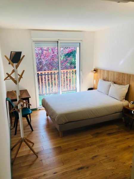 Habitación doble con suelo de madera y terraza con vistas al jardín en Logis Hôtel Les Tilleuls