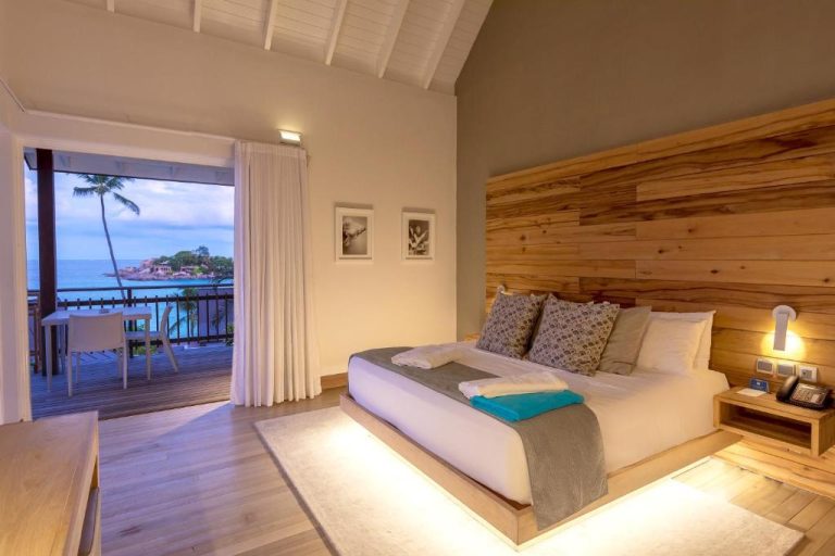 Habitación de lujo con cama doble, cabecero de madera y terraza con vista al mar en CaranaBeach