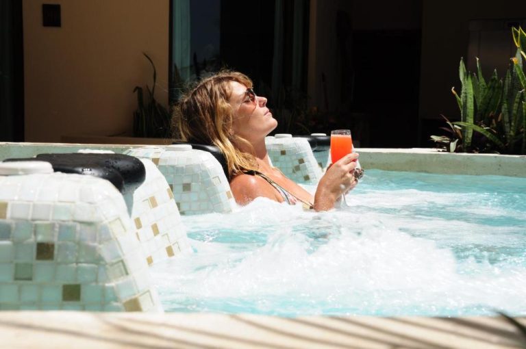 Mujer relajándose en el jacuzzi exterior con mosaicos del El Taj Oceanfront and Beachside Condo Hotel