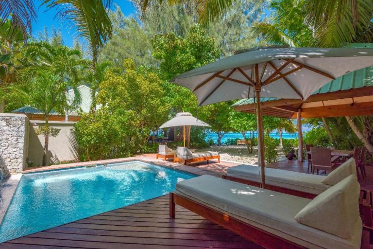Piscina privada con tumbonas y sombrillas junto a la playa en Denis Private Island Seychelles