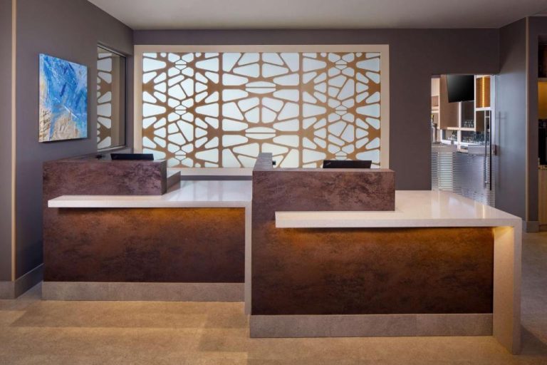 Recepción moderna con mostrador iluminado y panel decorativo del Hyatt Place Aruba Airport