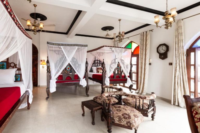 Habitación de lujo con camas de dosel de madera tallada y decoración árabe en Tembo House Hotel Zanzíbar