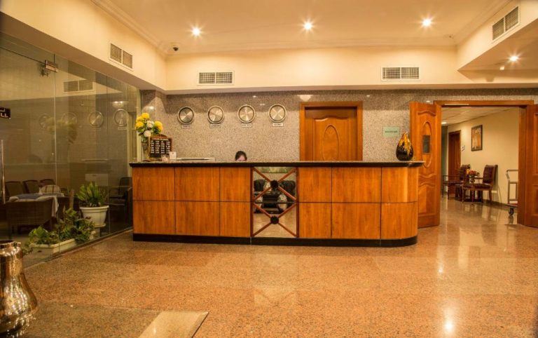 Recepción principal del Le Park Hotel con mostrador de madera y relojes mundiales en la pared