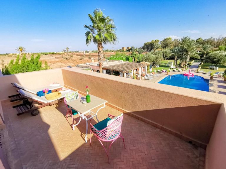 Terraza con mesa y sillas coloridas con vistas a la piscina exterior de La Villa Des Golfs & PinkCactus