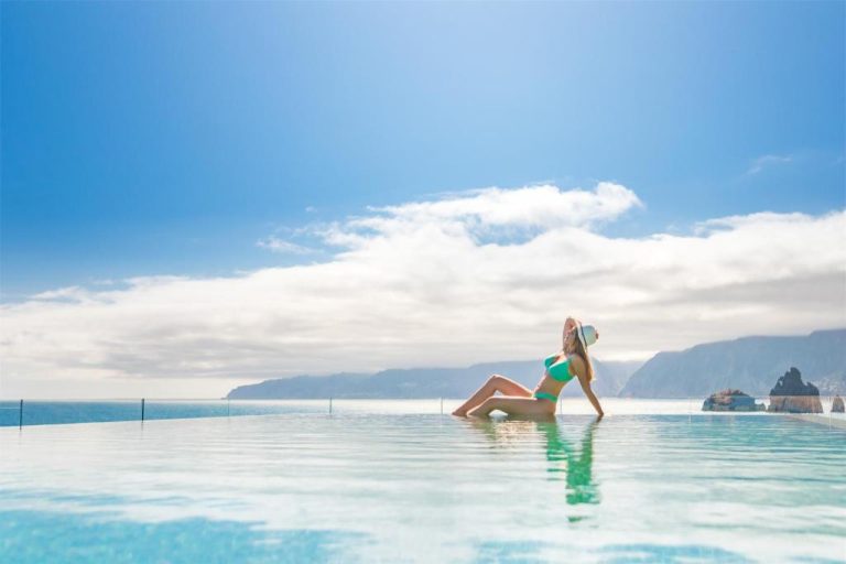 Mujer relajándose en la piscina infinita del Aqua Natura Bay con vistas al mar y acantilados