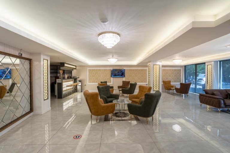 Elegante lobby del TAMARA Business Otel con sillones dorados, lámpara de araña y zona de recepción