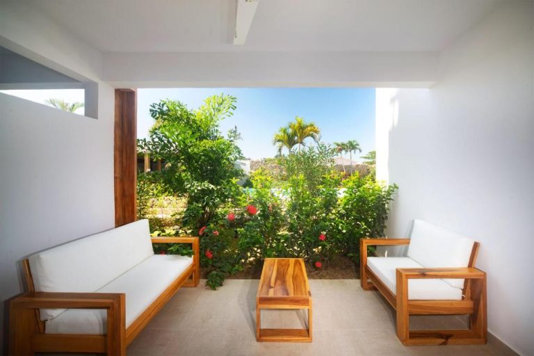 Terraza con sofás de madera y jardín tropical en Naboo Resort & Dive Center Adults Only