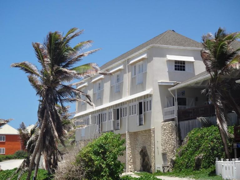 Fachada exterior del Atlantis Historic Inn con palmeras y vegetación tropical junto a la playa