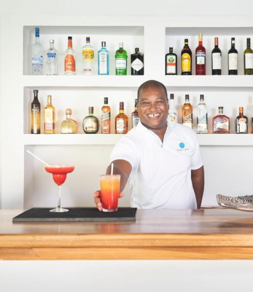 Bartender sonriente sirviendo cócteles tropicales en la barra del bar del Naboo Resort Adults Only
