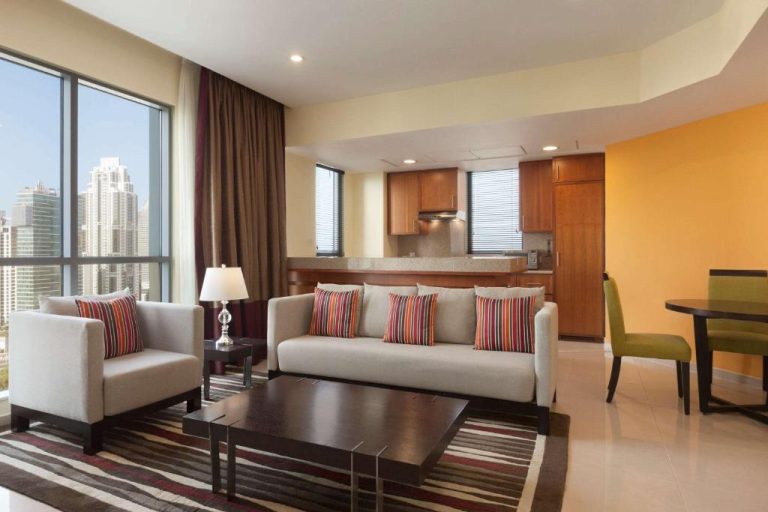 Salón moderno con cocina integrada y vistas al skyline en Ramada by Wyndham Downtown Dubai