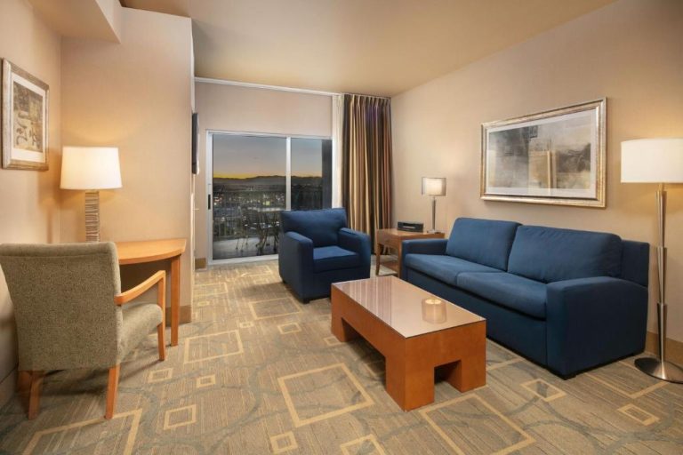 Suite con sala de estar, sofá azul y vistas al atardecer en The Platinum Hotel Las Vegas