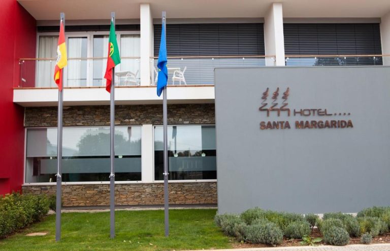 Fachada exterior del Hotel Santa Margarida con banderas y jardín en primer plano