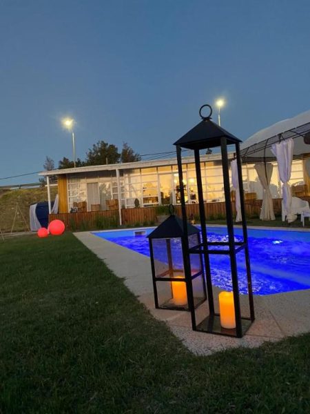 Piscina exterior iluminada de noche con faroles y velas en Hotel Terrazas del Río Negro