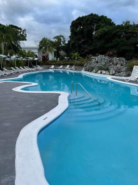 Piscina exterior de forma libre con tumbonas y jardines tropicales del Jamaica Palace Hotel