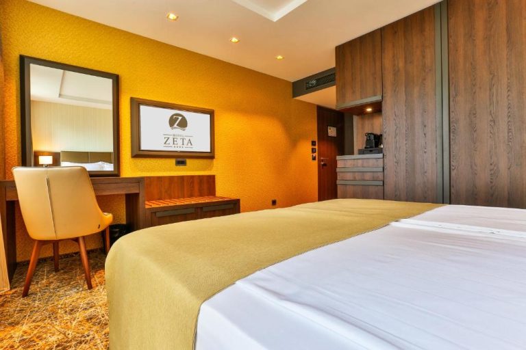 Habitación doble con cama grande y escritorio en el Hotel Zeta, decoración en tonos dorados