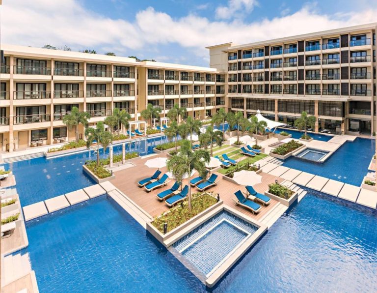 Amplia piscina exterior con tumbonas azules y palmeras del Henann Park Resort en Boracay