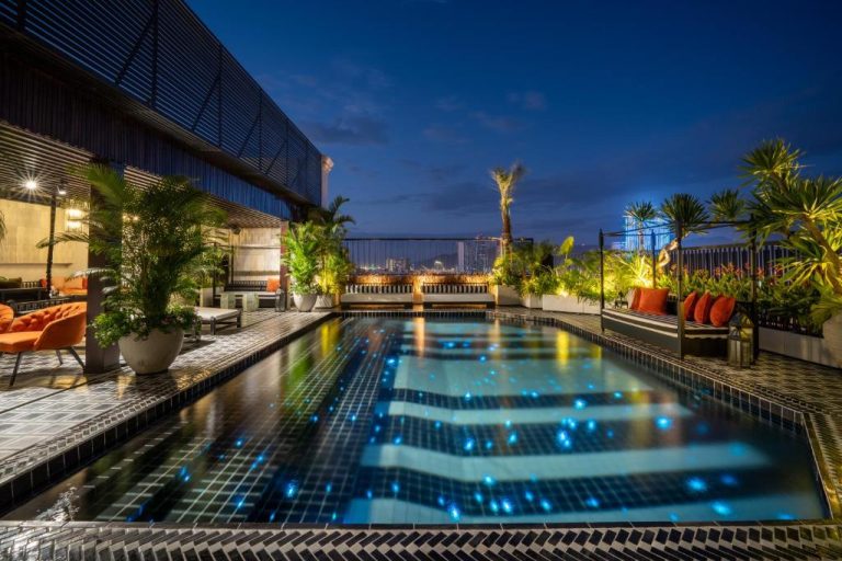 Piscina en la azotea iluminada de noche con vistas a la ciudad en Sanouva Da Nang Hotel