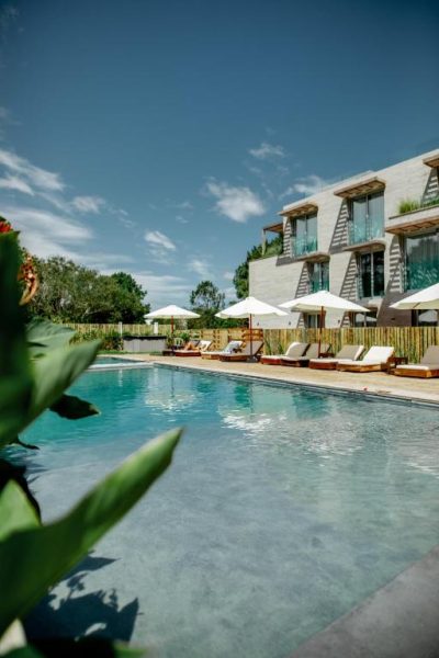 Piscina exterior con tumbonas y sombrillas del Casagrande Hotel & Beach Club rodeada de vegetación tropical